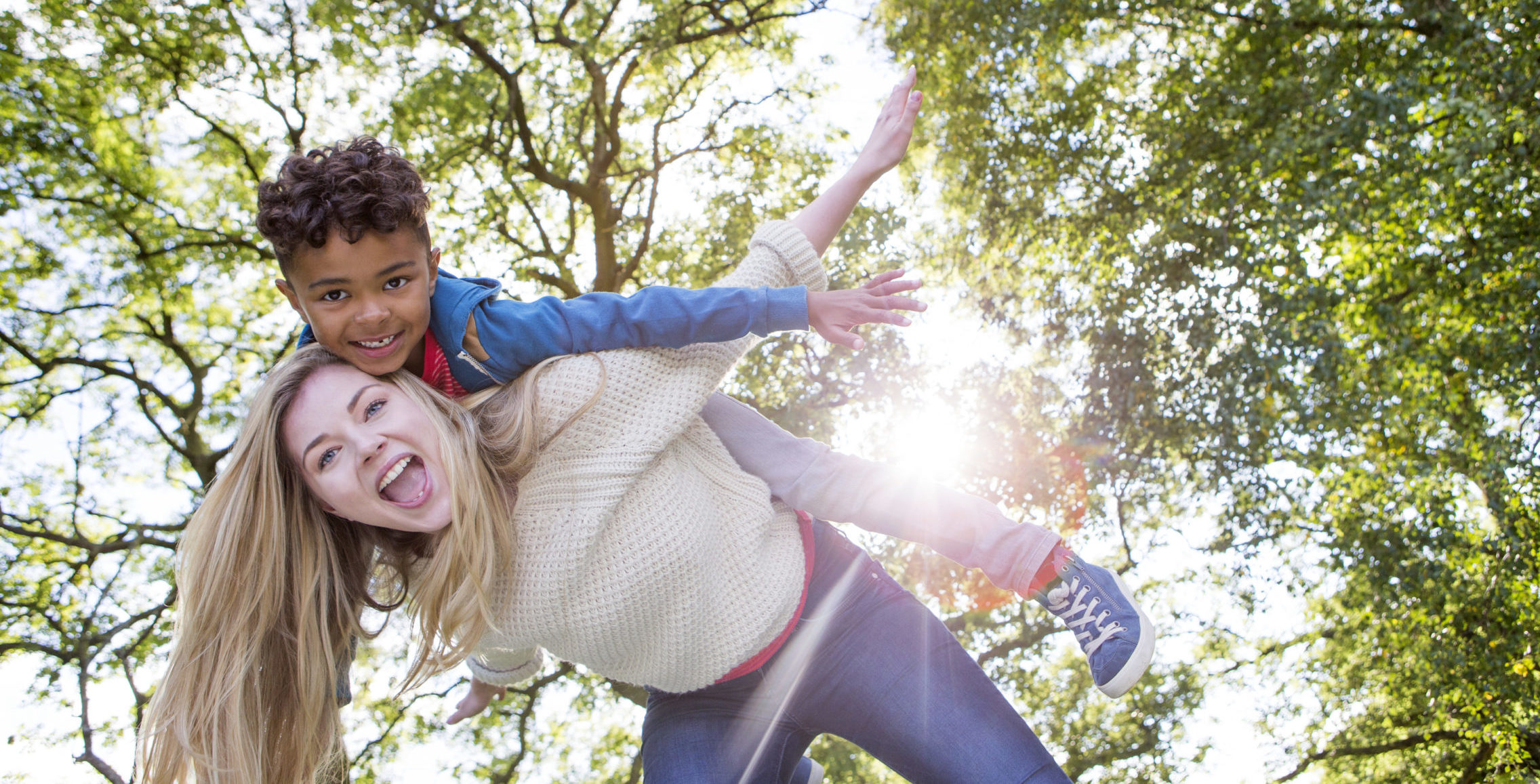 A happy little boy playing with a woman in the park