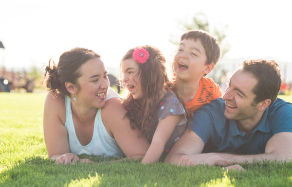 Mom, dad, and their two young kids pose on the grass