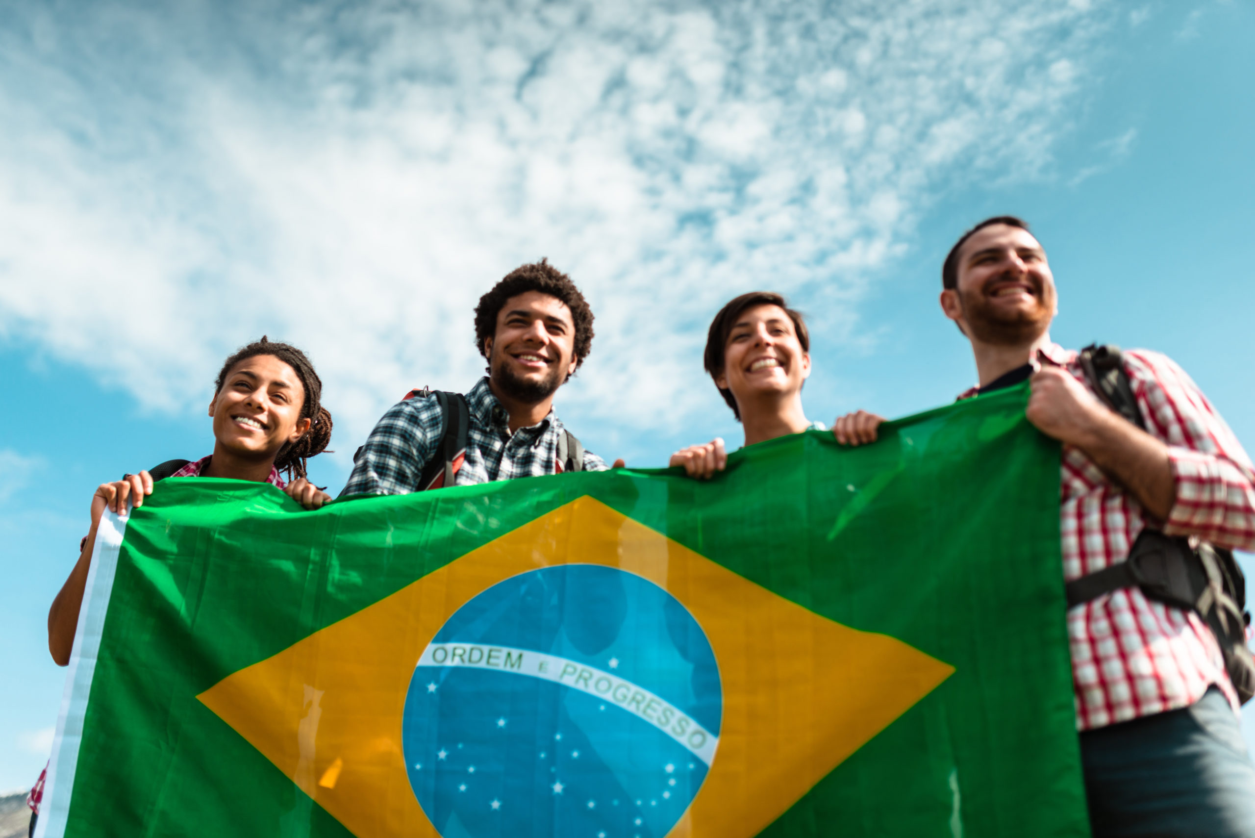 four people holding Brazilian flag
