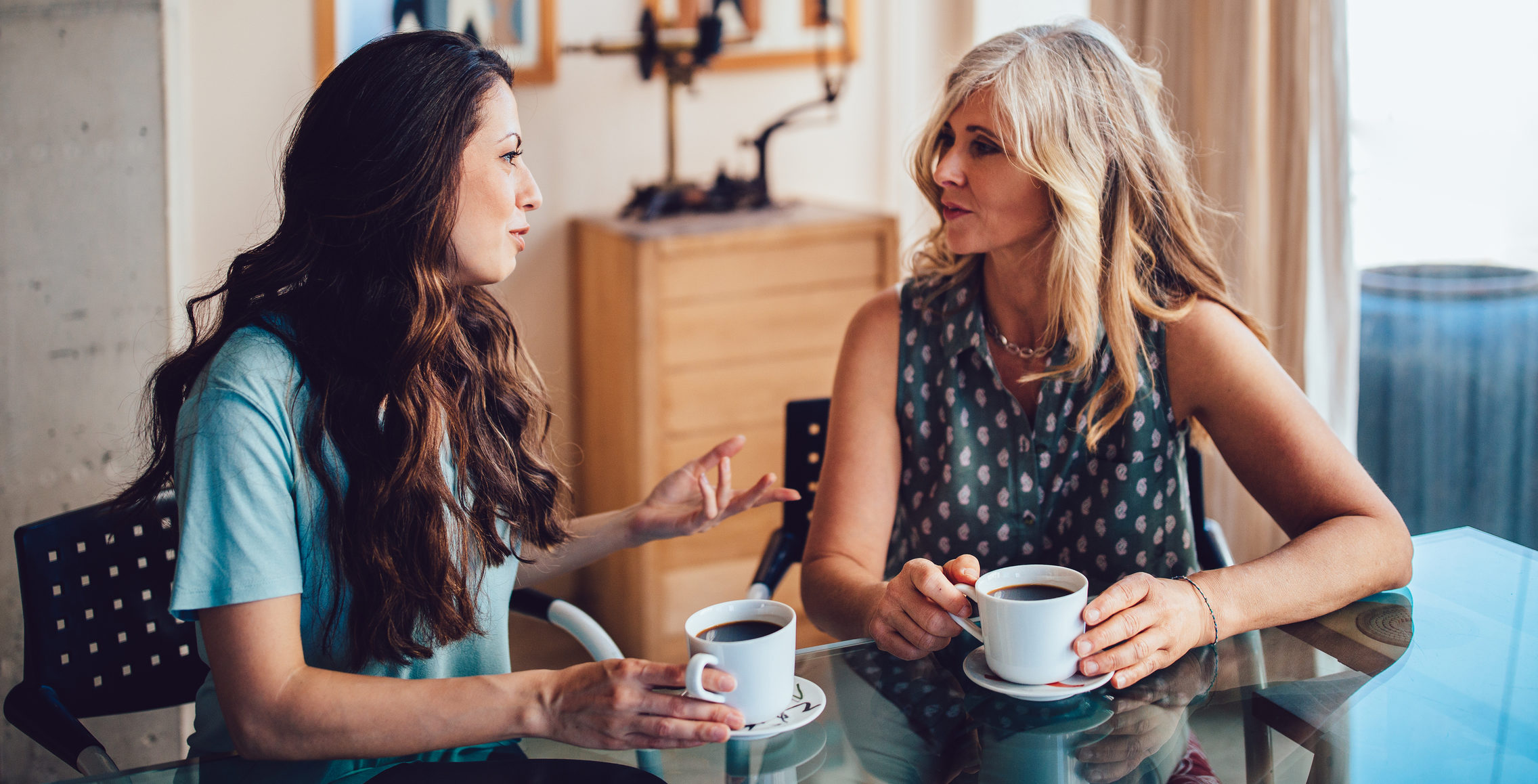 daughter talking to mom while drinking coffee at dining table