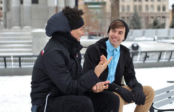 two men sitting on a bench in winter