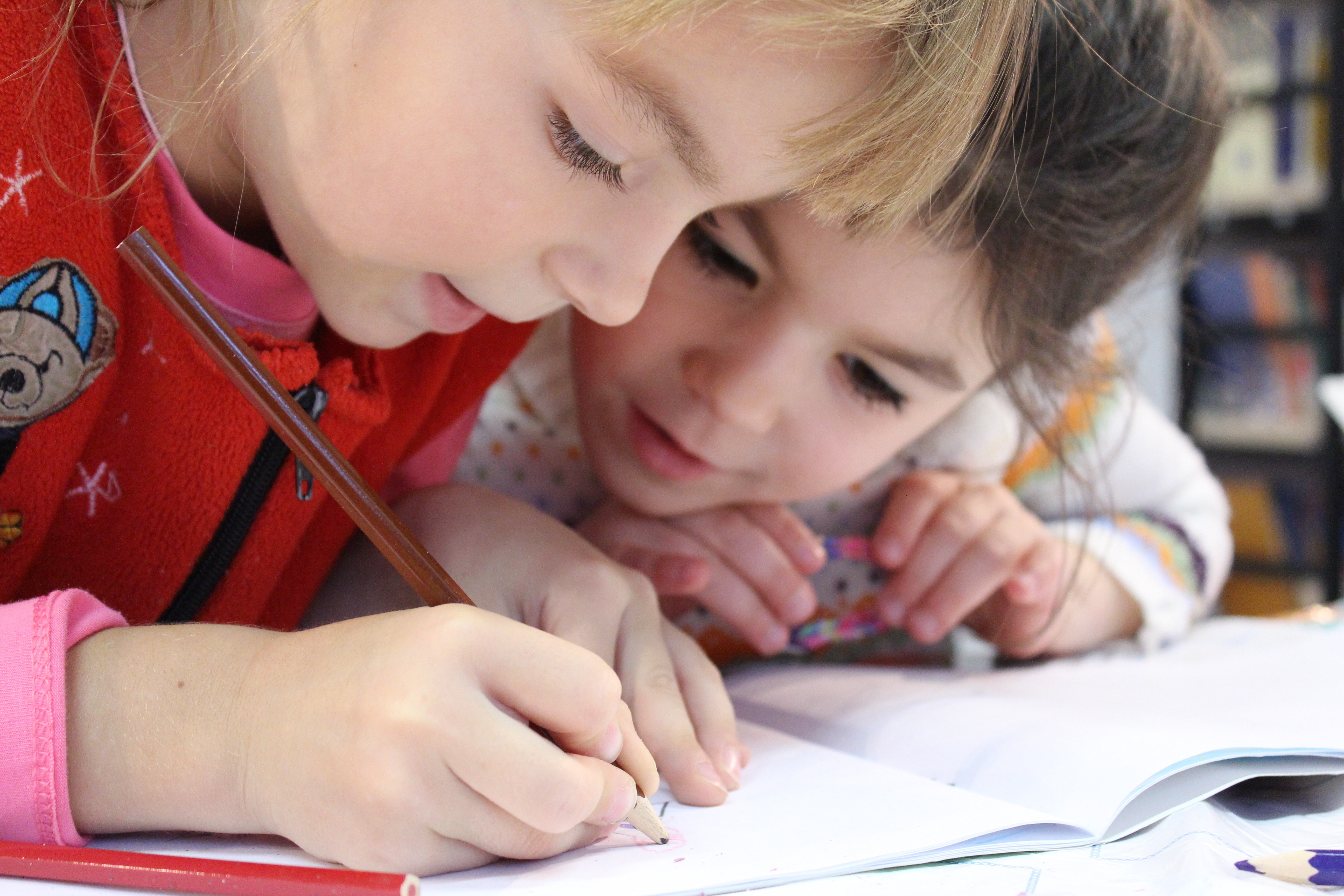 Two girls coloring in a notebook