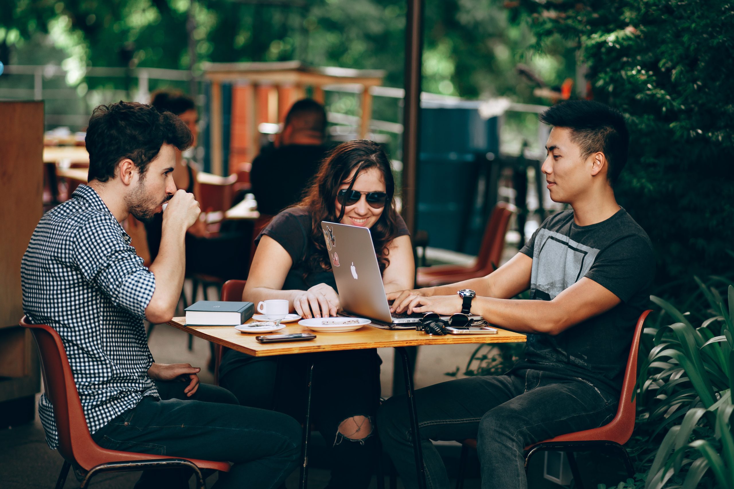 Three people at coffee shop looking at laptop