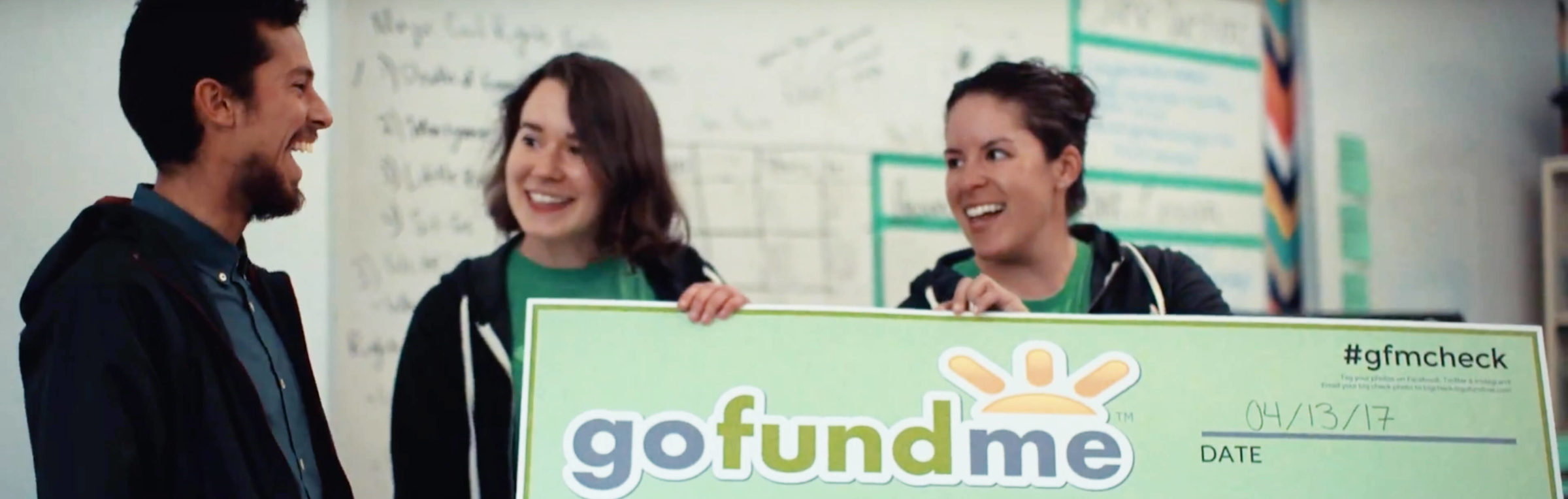 Two GoFundMe employees present a check for $1,000 to a teacher