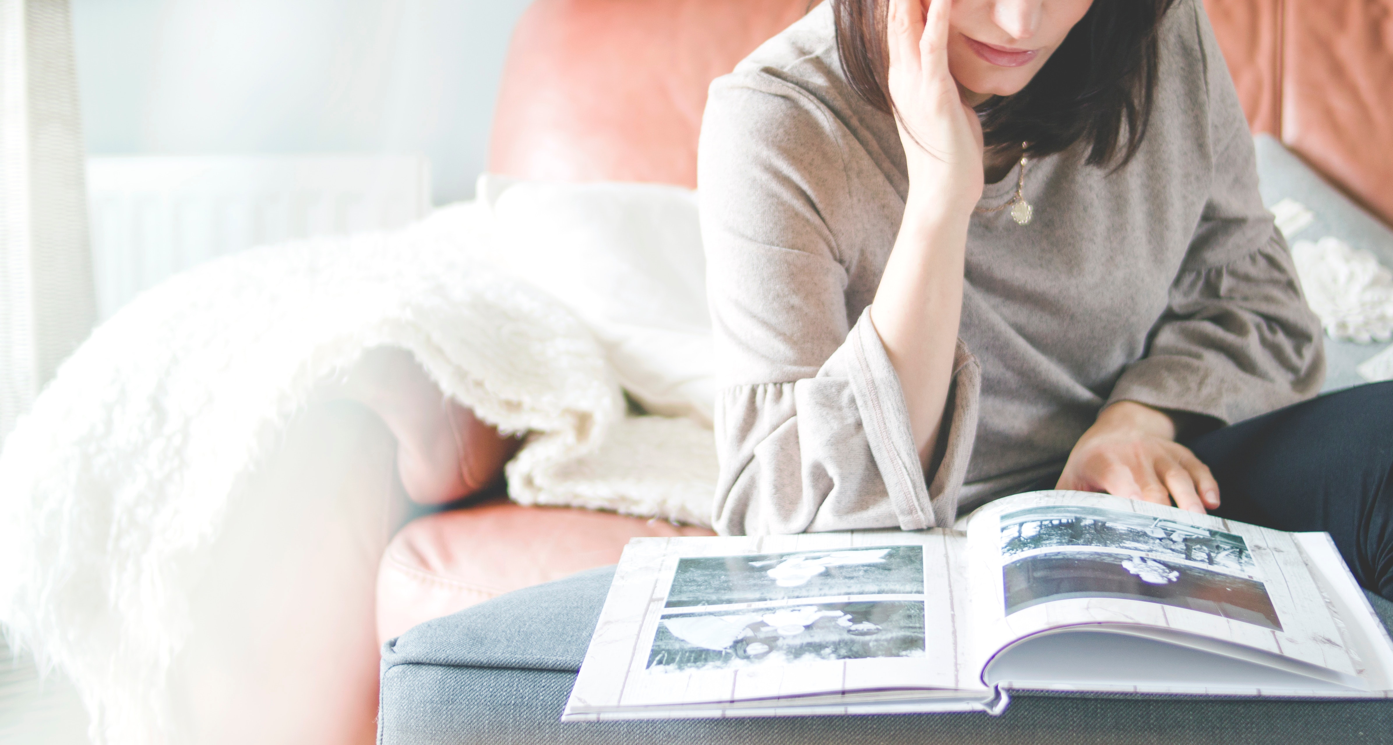 Woman sitting on a couch looking at a photo album