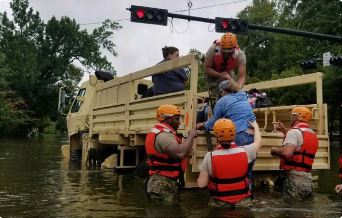 Rescue workings help woman into the back of a rescue truck during a flood