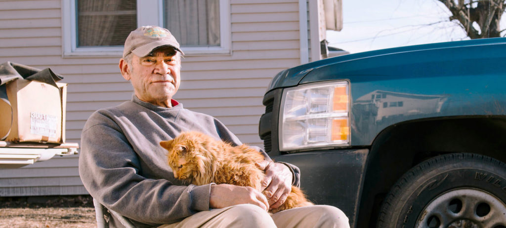elderly man sitting outside with his cat on his lap