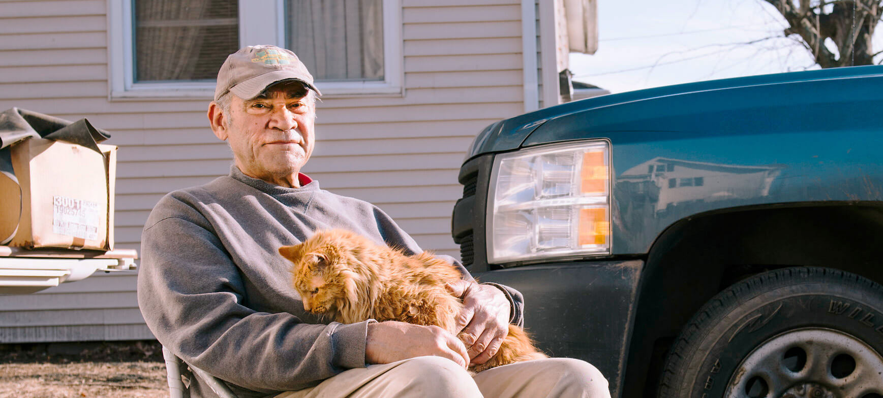 Elderly man sitting outside with his cat on his lap