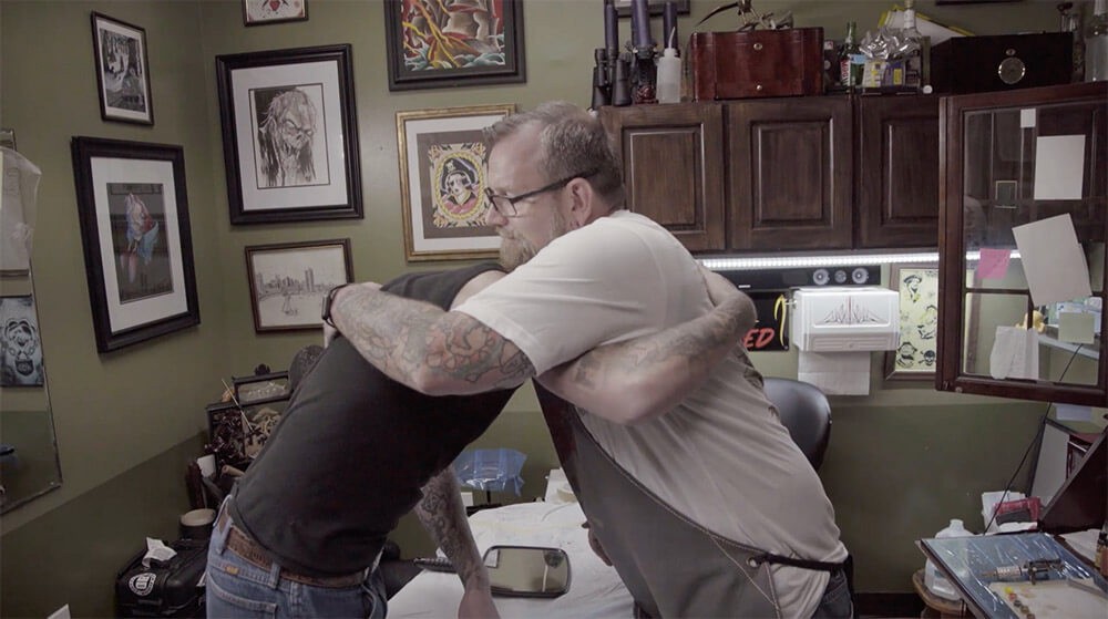 two people hugging in tattoo parlor