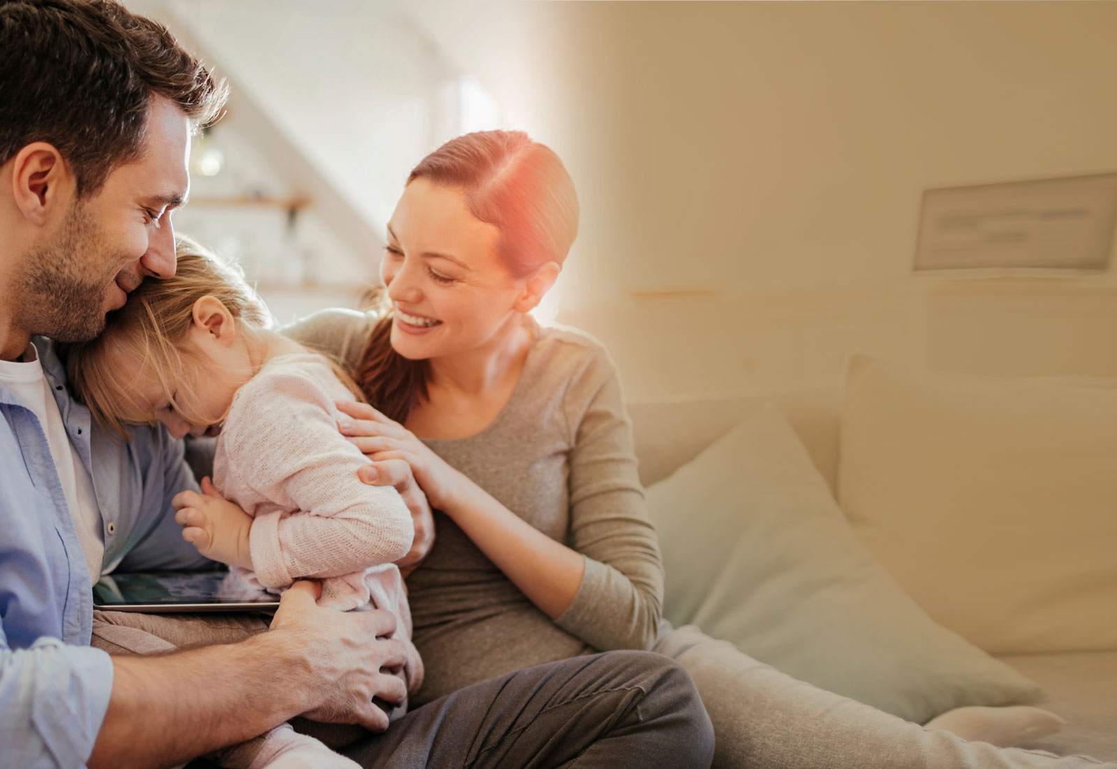 man and woman hugging girl child on couch