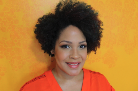 Ijeoma Oluo wearing orange shirt against a yellow background