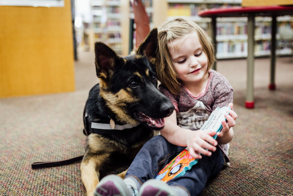 little girl in a library with her support dog