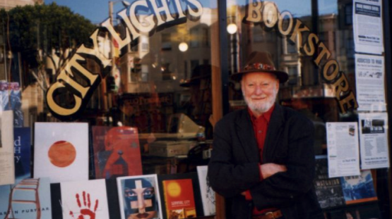 A man in hat standing in front of a bookstore