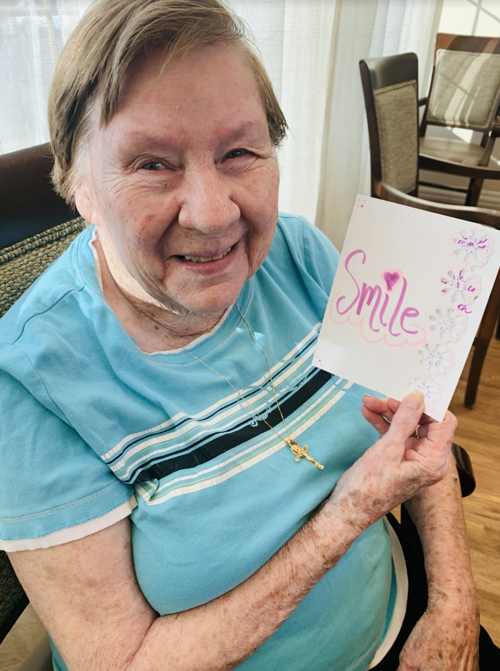 Elderly woman holding up a card that says smile