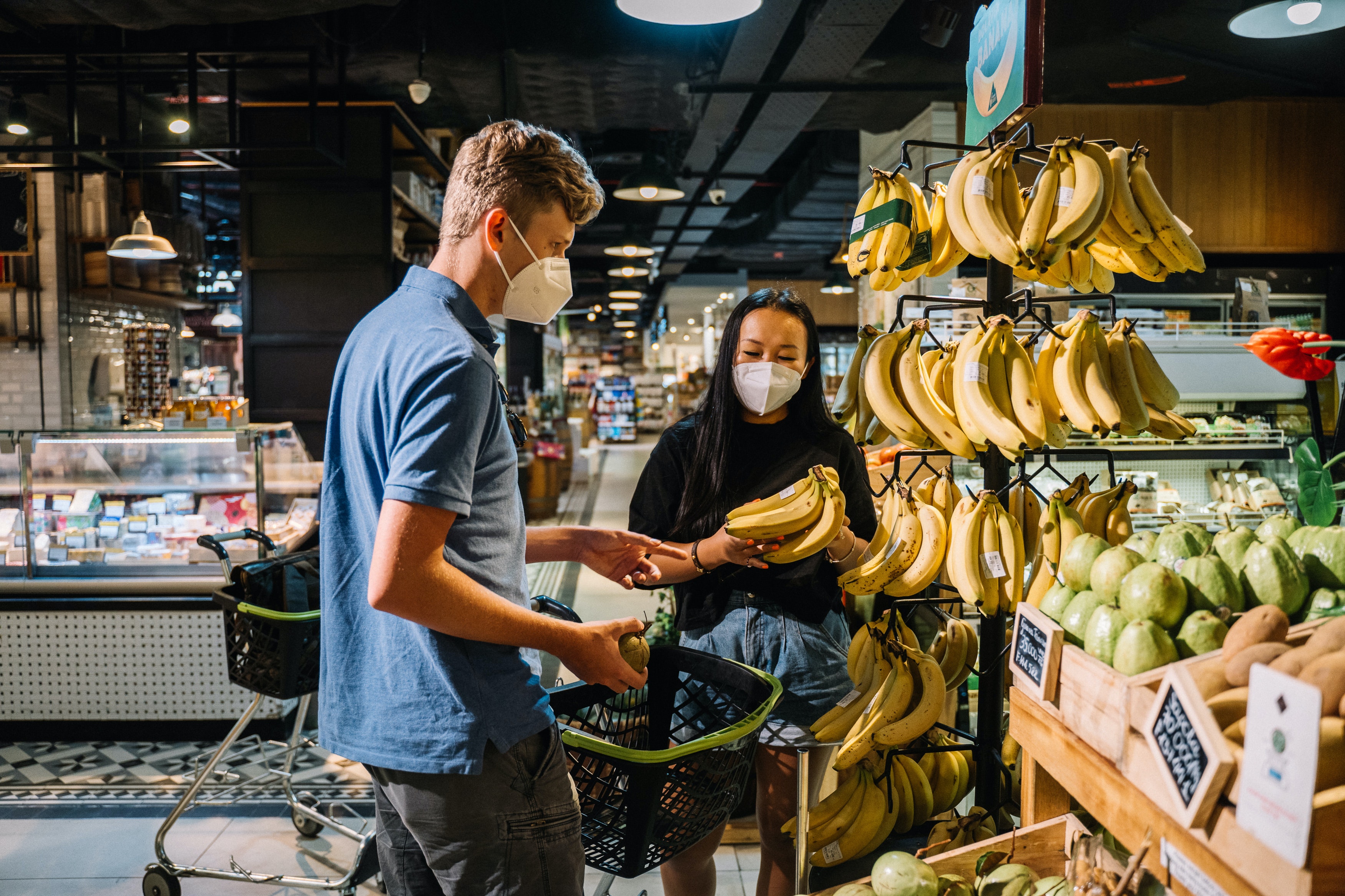 A man and woman wearing masks in the grocery store