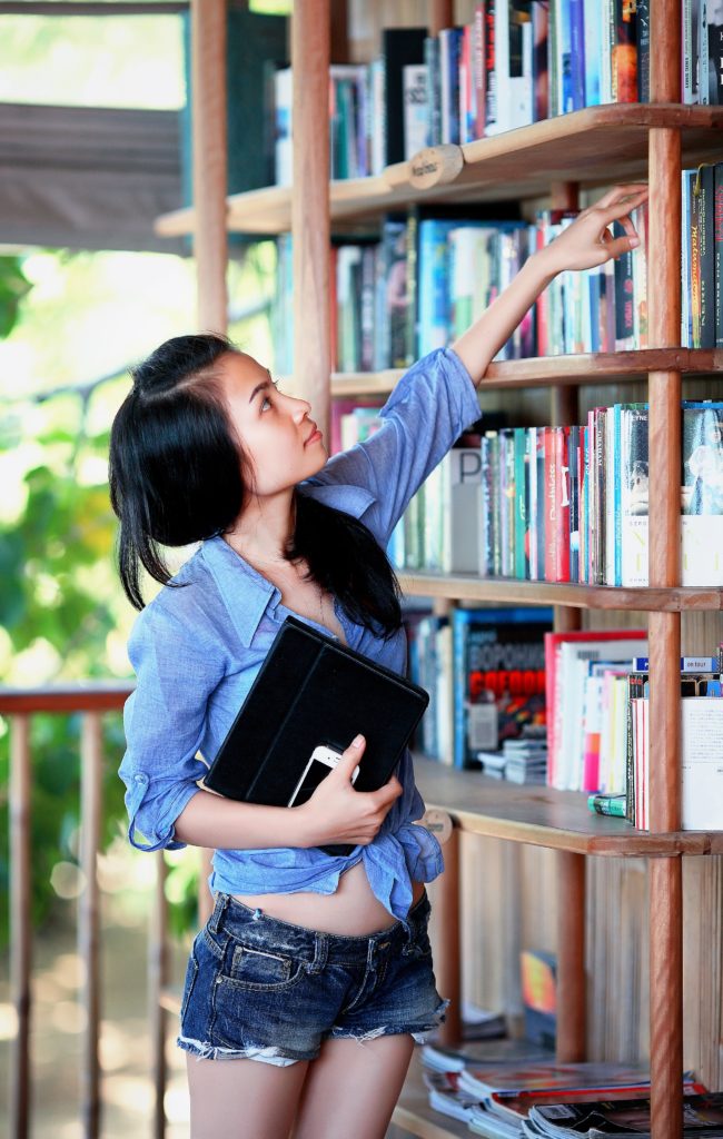 girl placing books on a bookshelf