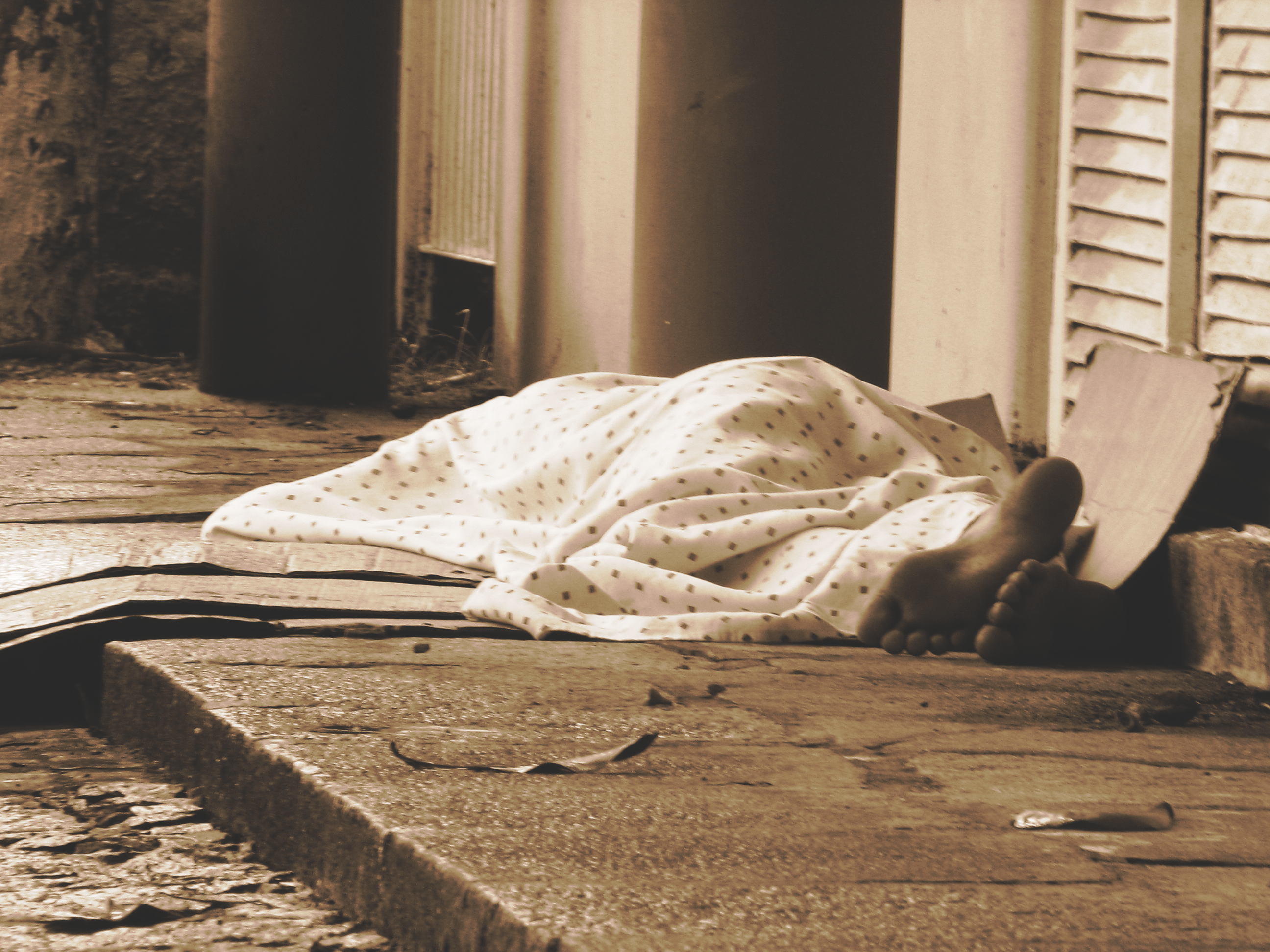 a homeless person sleeps on the street at night