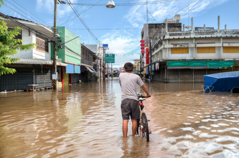 man standing in flood water with a bicycle
