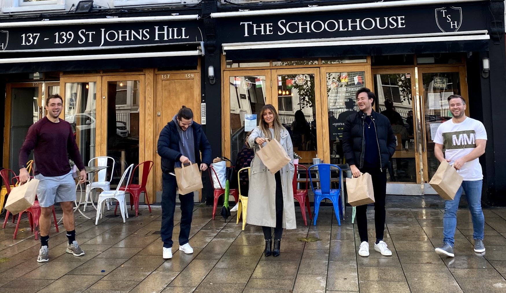 Schoolhouse staff hold up lunch bags